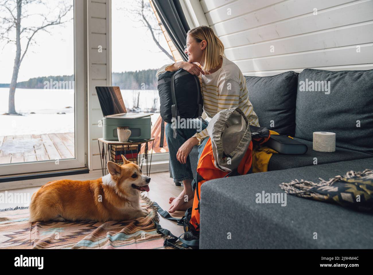 Donna con zaino seduto sul divano da cane a casa Foto Stock