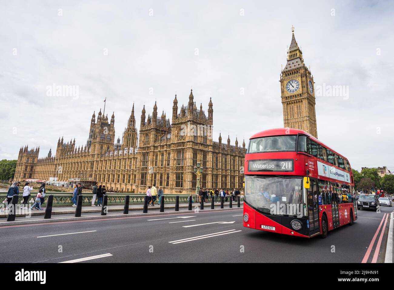 Un autobus rosso di Londra attraversa Westminster Bridge di fronte al Parlamento di Londra visto nel maggio 2022. Foto Stock