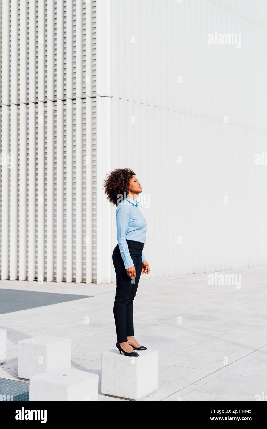 Afro businesswoman in piedi su blocco di cemento Foto Stock
