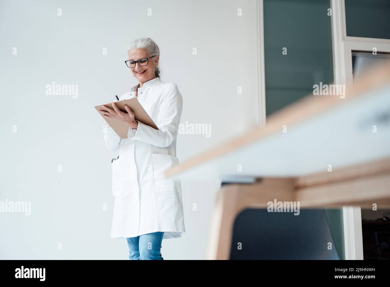 Buon medico in piedi e scrivere sugli appunti Foto Stock
