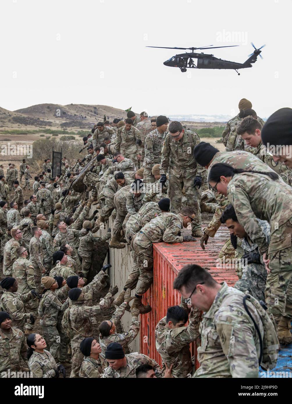 Fort Carson, Stati Uniti. 23rd maggio 2022. I soldati dell'esercito degli Stati Uniti assegnati alla divisione di fanteria 4th, aiutano a spingersi l'un l'altro su un muro di container fangoso durante l'evento di sfida Utah Beach a Fort Carson, 23 maggio 2022 a Fort Carson, Colorado. L'evento tenuto durante la settimana di Ivy richiede che le squadre dei soldati trasportino un pneumatico di 300-libbra sopra un corso fangoso dell'ostacolo. Credito: SSgt. Matthew Lumagui/U.S. Army/Alamy Live News Foto Stock