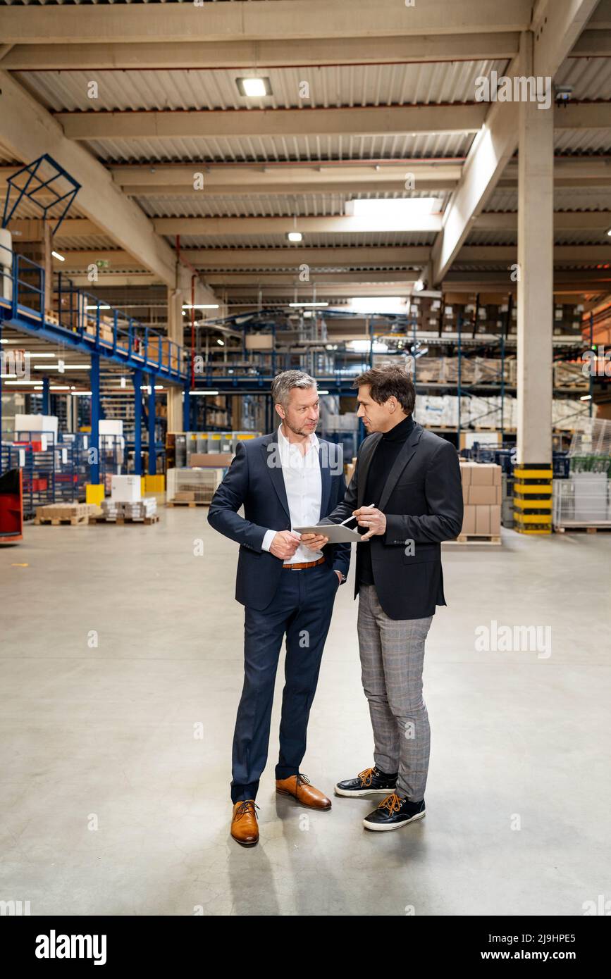Uomini d'affari maturi che discutono in riunione alla fabbrica Foto Stock