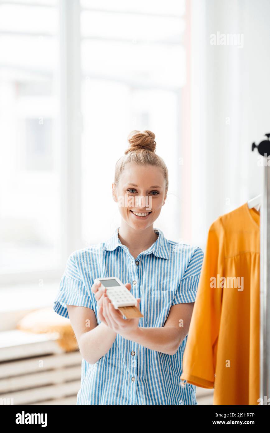 Stilista di moda che tiene lettore di carte di credito Foto Stock