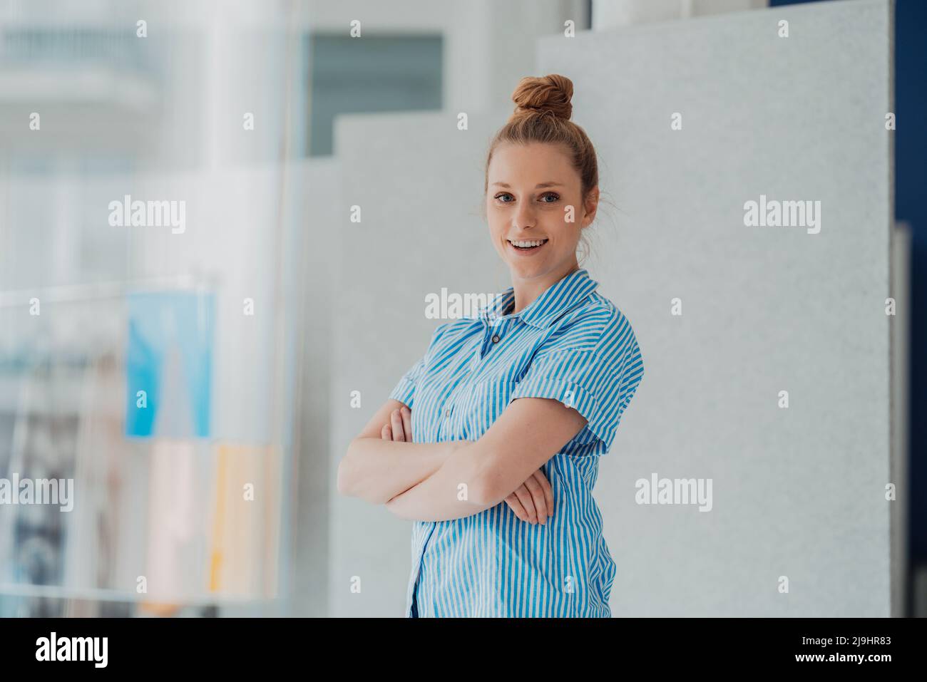 Stilista fiducioso con le braccia incrociate in studio Foto Stock