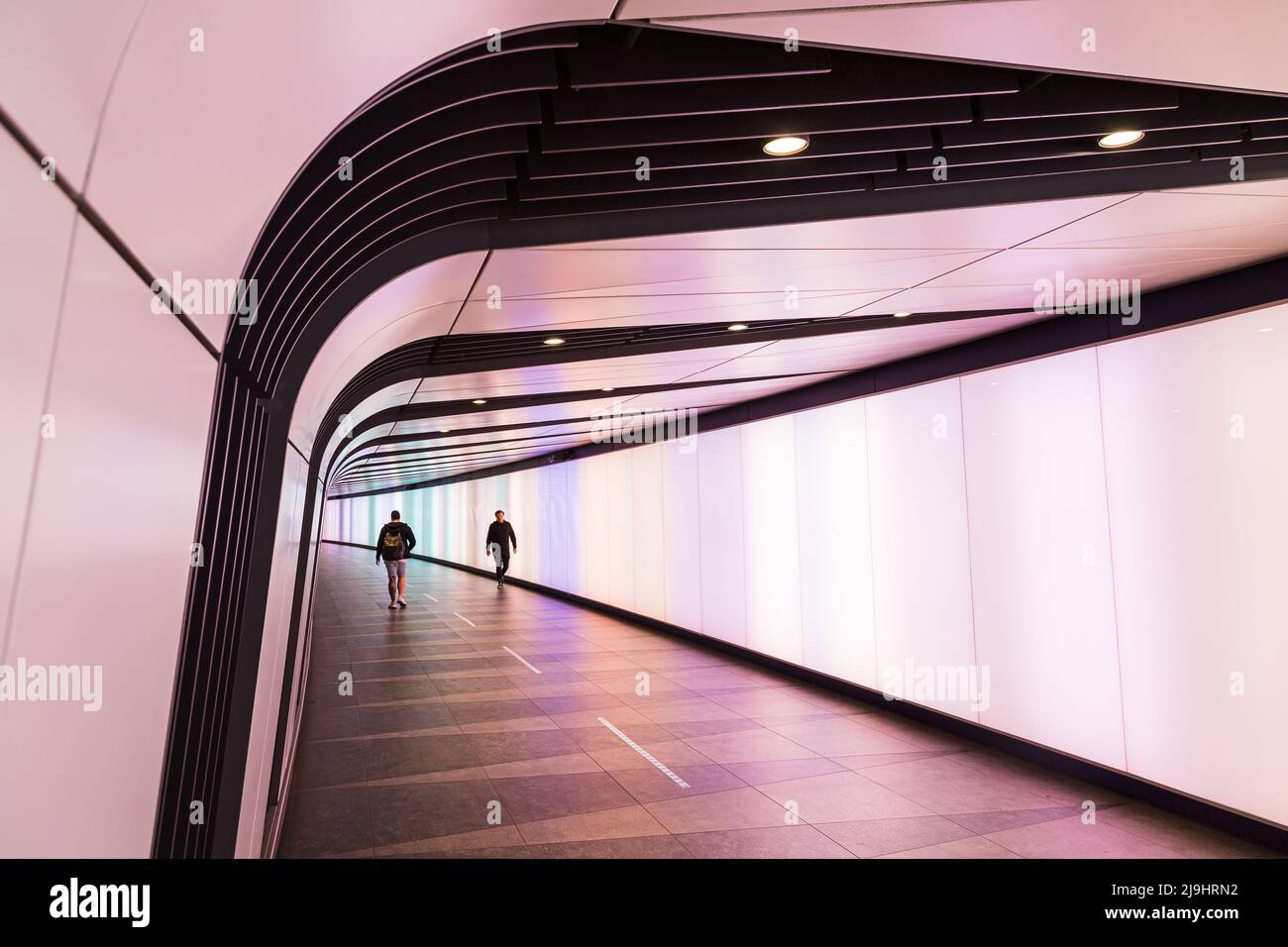 Due uomini passano l'uno all'altro nel tunnel leggero di Kings Cross che collega la stazione ferroviaria internazionale e la metropolitana di Londra, raffigurata nel maggio 2022. Foto Stock