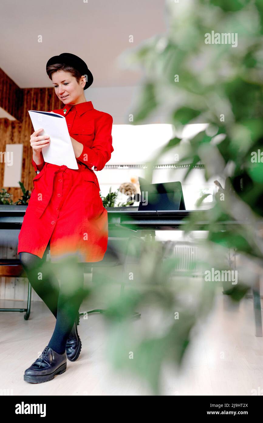 Donna iscritto in libro in piedi alla scrivania in ufficio Foto Stock
