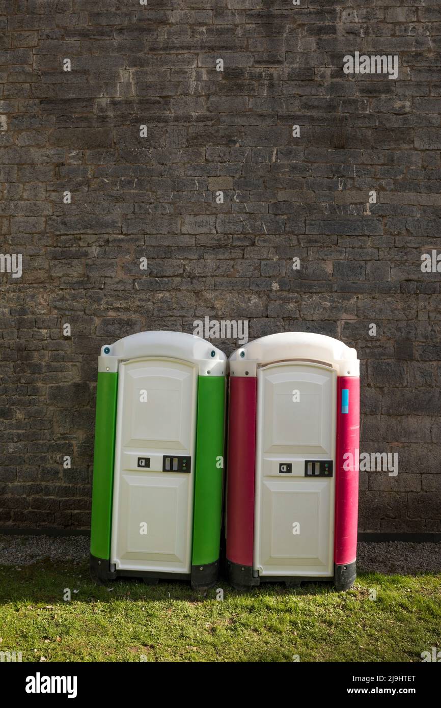 Due bagni portatili affiancati di fronte alla parete in mattoni Foto Stock
