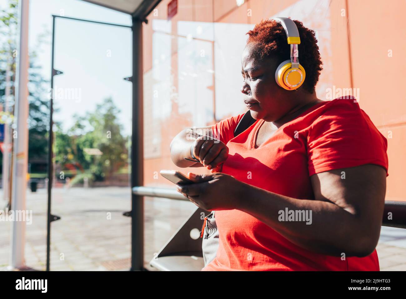 Donna che tiene lo smart phone controllare l'ora in giorno di sole Foto Stock