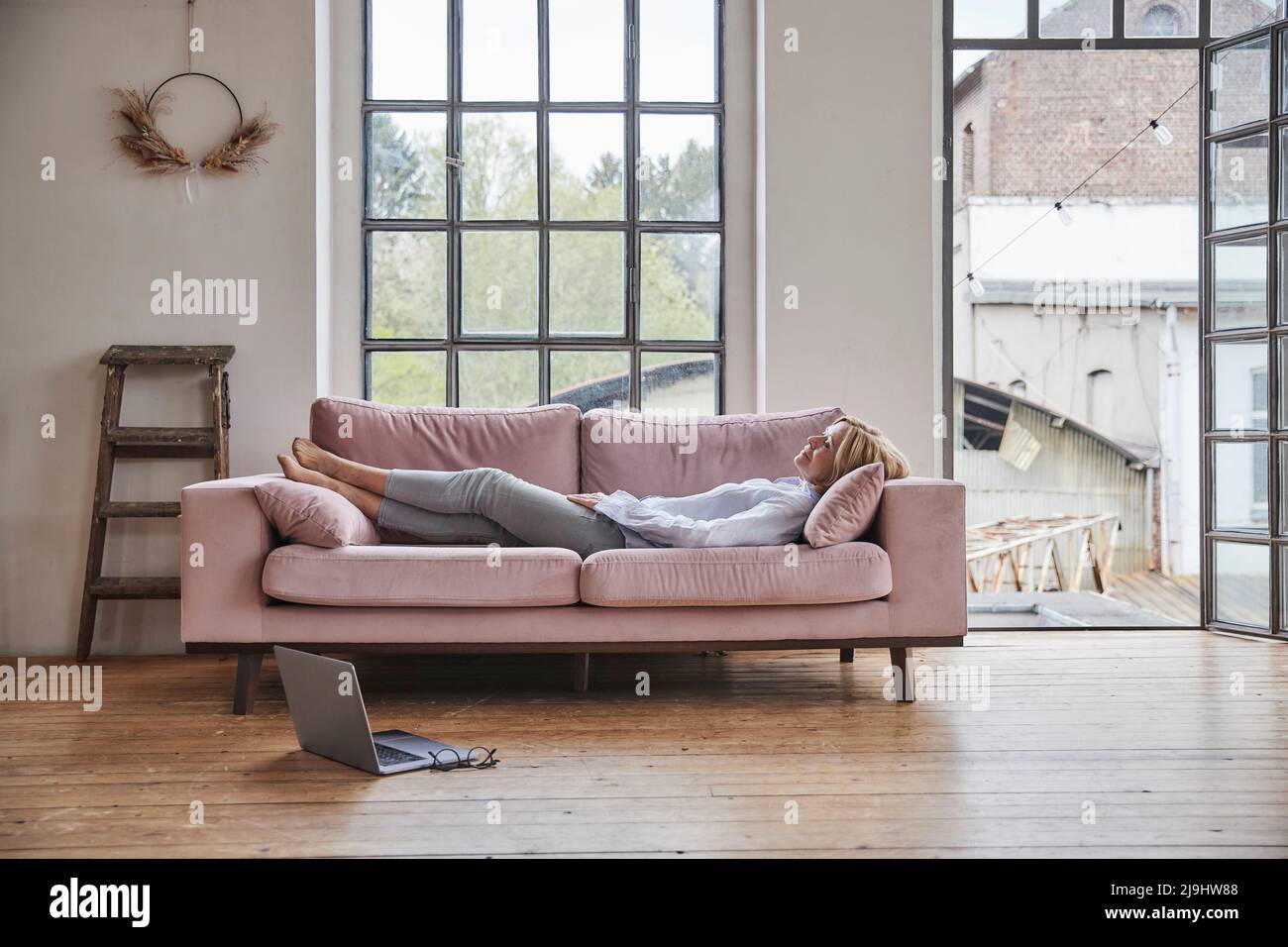 Donna rilassante sul divano nel soggiorno di casa Foto Stock