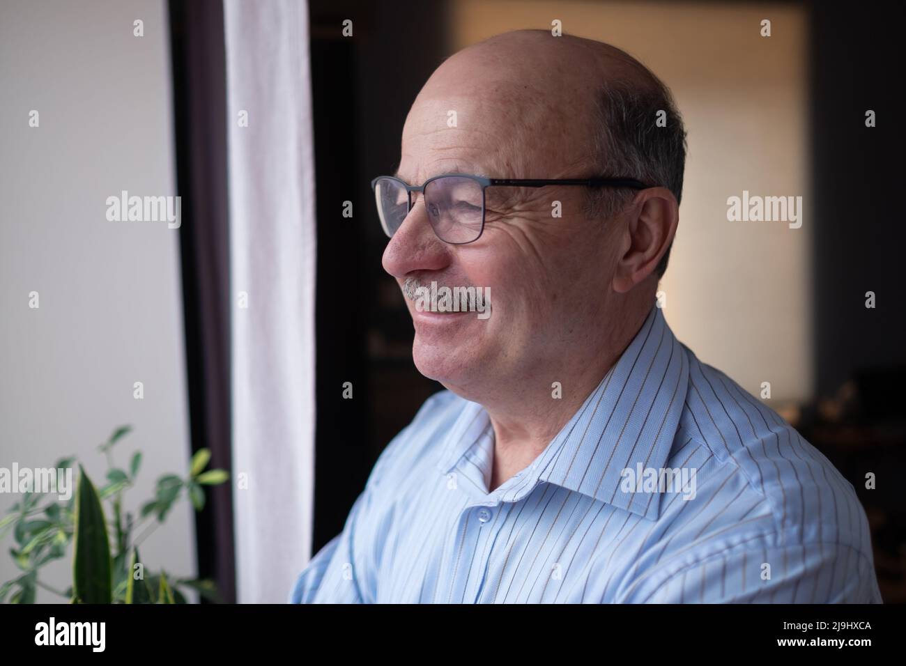 Anziano pensivo anziano anziano maturo in occhiali guardando in lontananza fuori dalla finestra, pensando. Buoni ricordi in mente. Foto Stock