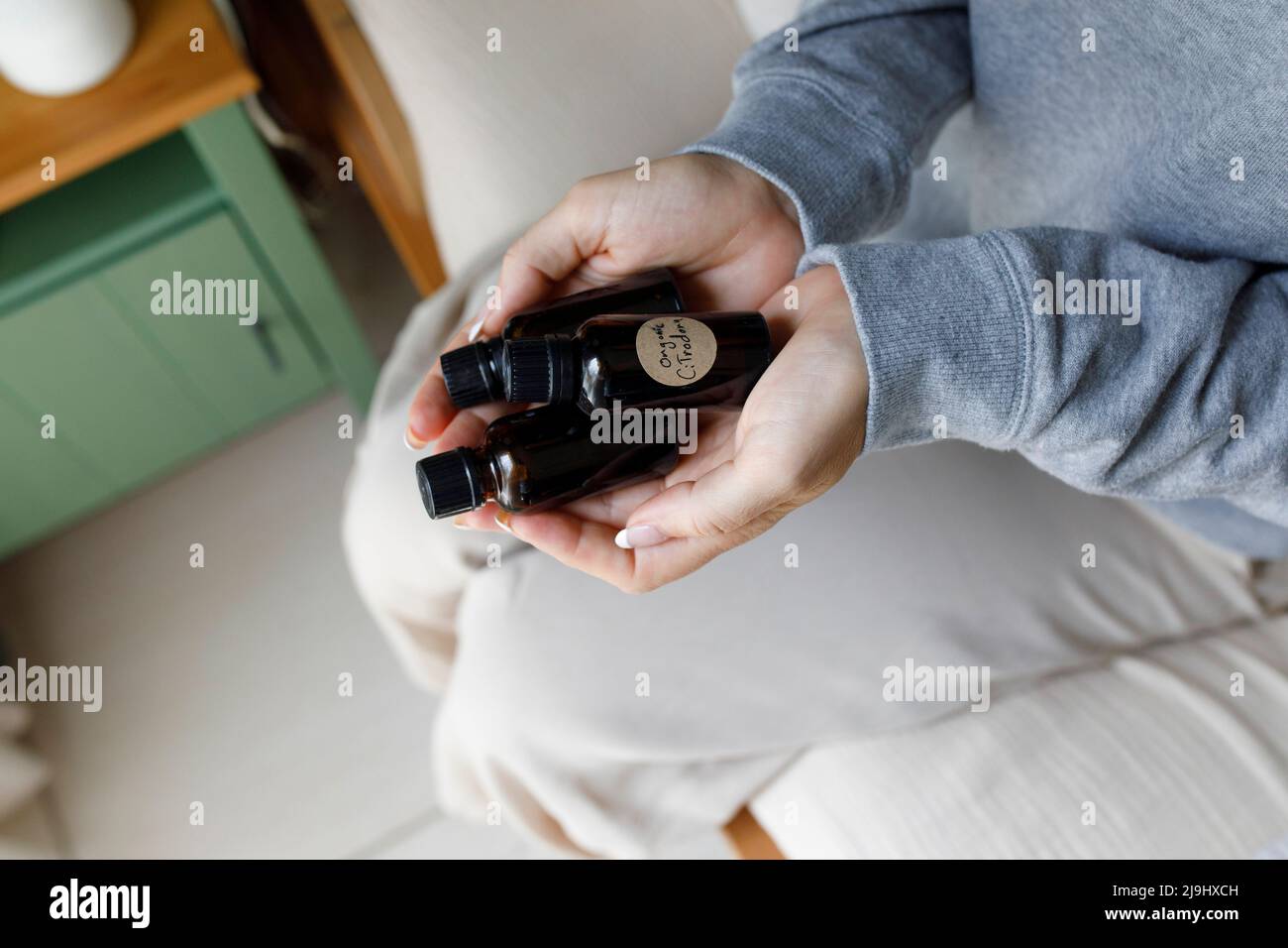Donna che tiene bottiglie d'olio essenziali a casa Foto Stock