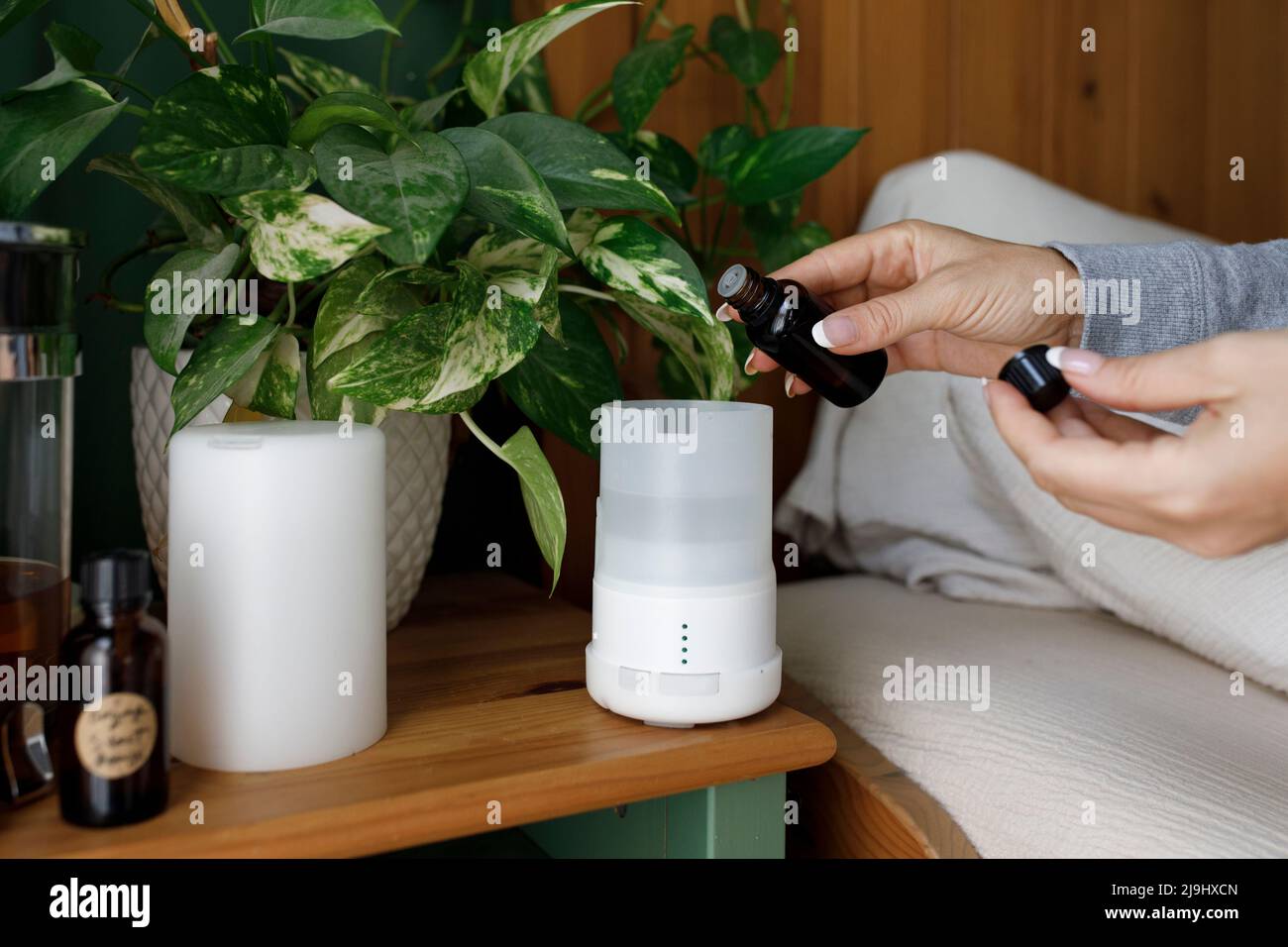 Mano di donna che versa l'olio essenziale nel diffusore d'aria a casa Foto Stock