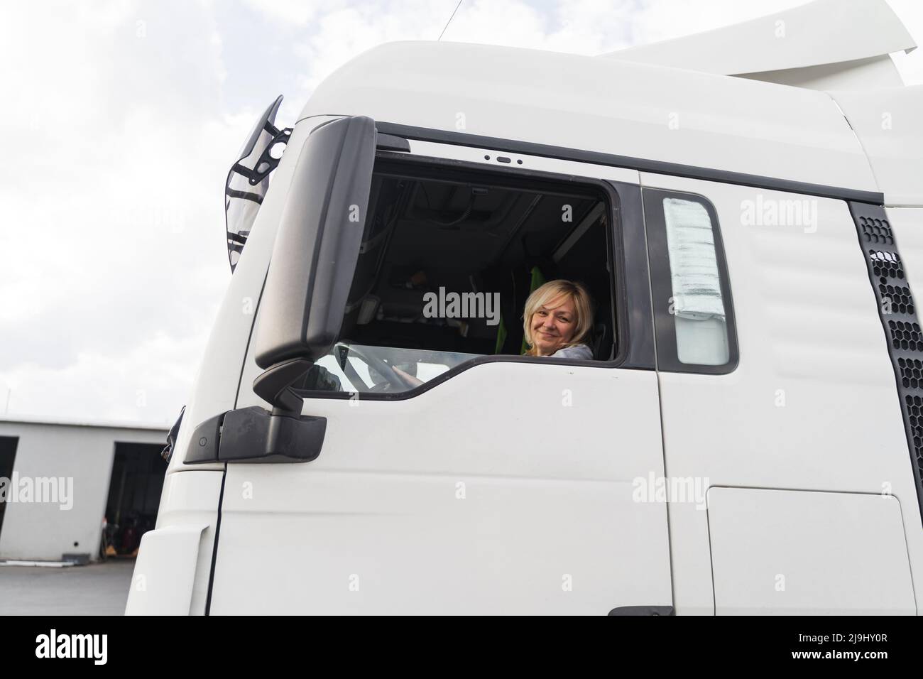 Donna caucasica di mezza età che guida il camion. donna di trucker, occupazione di industria di trasporto Foto Stock