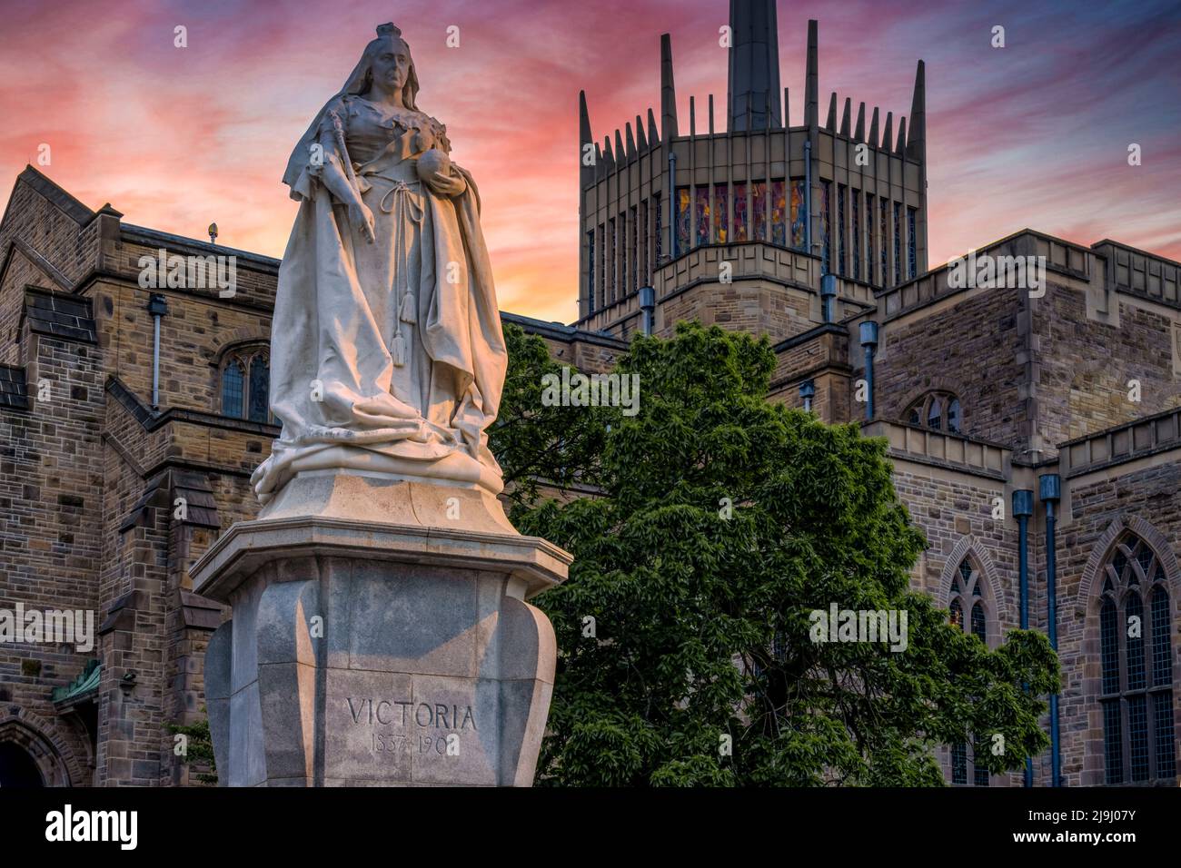 Cattedrale di Blackburn con statua della Regina Vittoria al tramonto. La statua è un monumento classificato di grado II situato a Blackburn, Lancashire, Regno Unito. Foto Stock
