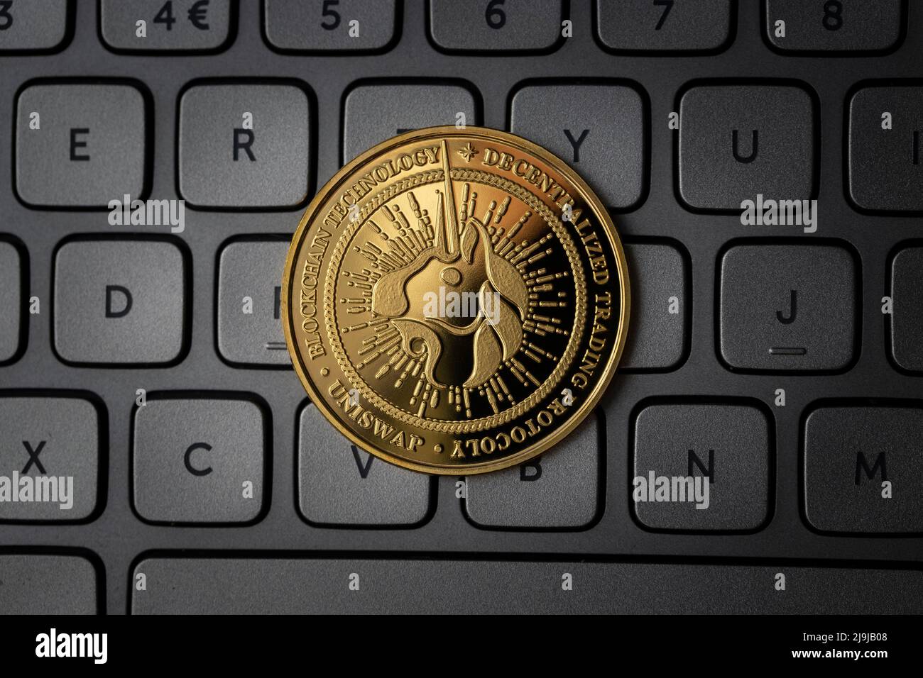 Uniswap UNI Cryptocurrency moneta fisica piazzato tastiera computer e parzialmente illuminato con luce naturale. Scatto macro. Foto Stock
