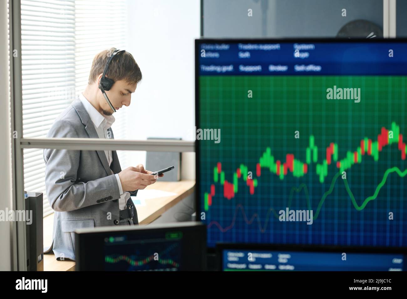 Consulente di investimento professionale che lavora in ufficio guardando le statistiche di trading su smartphone, vista laterale fuoco selettivo Foto Stock