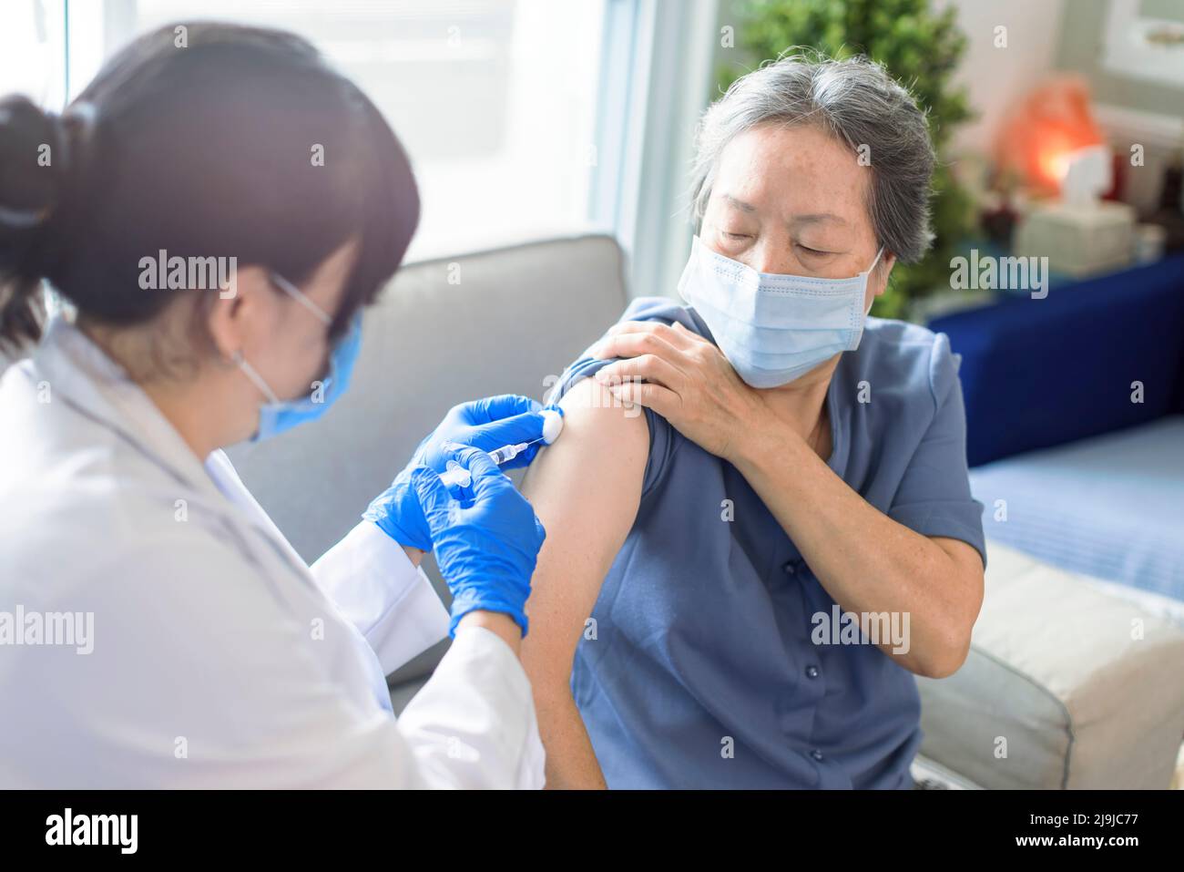 Donna anziana che riceve il vaccino. Medico che vaccina un paziente anziano contro l'influenza, il covid-19, la polmonite o il coronavirus. Foto Stock
