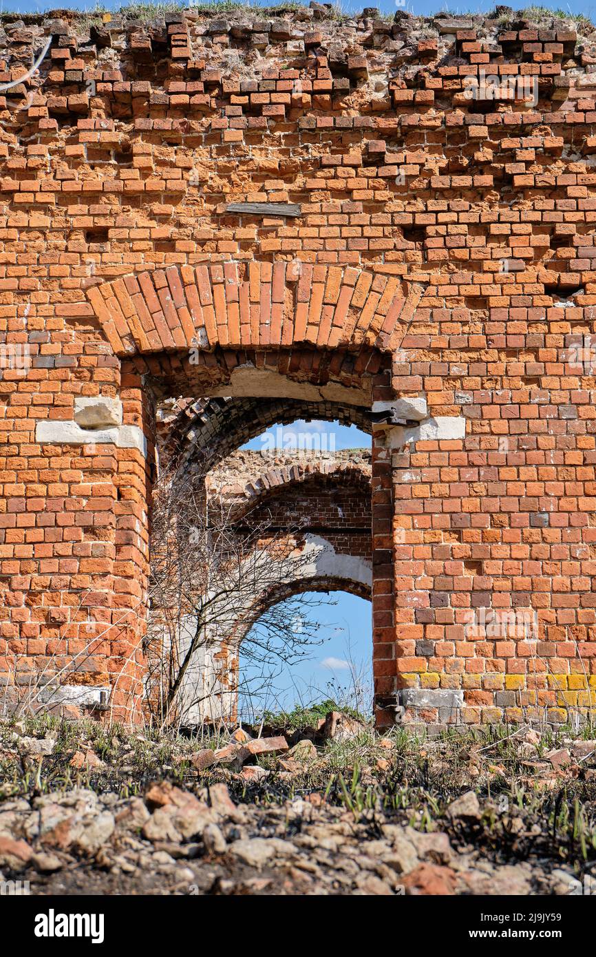 Un'antica chiesa cristiana in rovina in mattoni rossi d'estate di giorno contro un cielo blu. Foto Stock