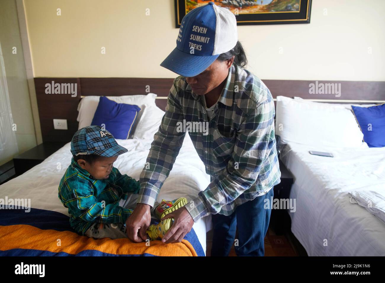 Kathmandu, Nepal. 24th maggio 2022. Fratello maggiore di Dor Bahadur Khapangi, 18 anni, adolescente maschile vivente più corto, Chi ha misurato una media di (2 piedi 4,9 in) aiuta il suo fratello più giovane messo sulla sua scarpa all'interno di una camera d'albergo prima di ricevere il certificato del detentore del record dei primati del mondo di Guinness a Kathmandu, Nepal il martedì 24 maggio 2022. (Credit Image: © Skanda Gautam/ZUMA Press Wire) Foto Stock