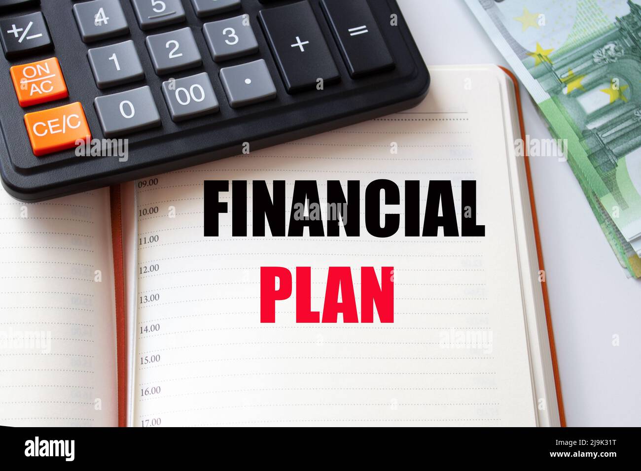 ISCRIZIONE della parola DEL PIANO FINANZIARIO in un taccuino, calcolatore e un mucchio di soldi. Foto Stock