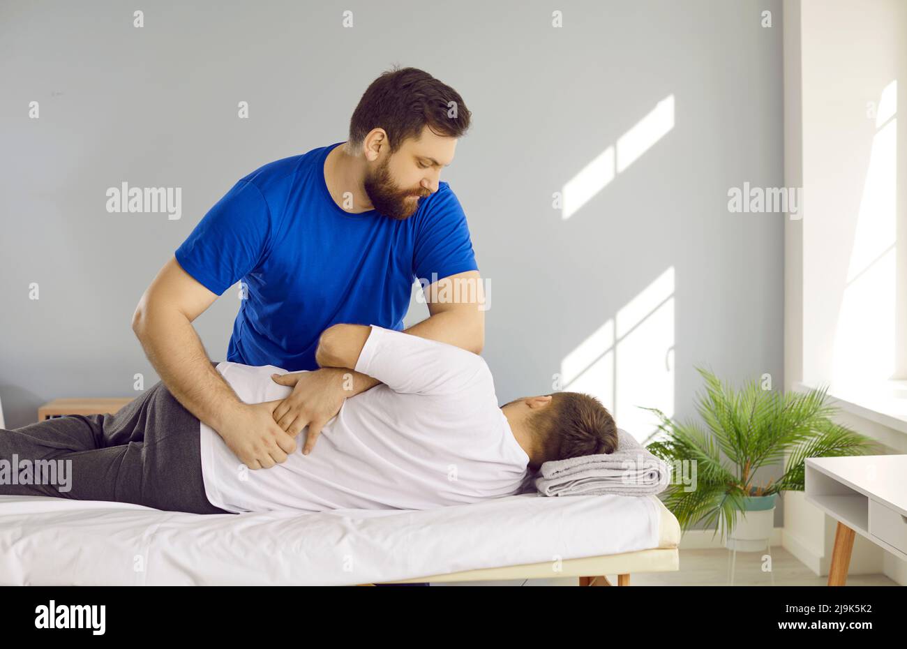 Chiropratico, fisioterapista, osteopata, o terapista manuale che aiuta l'uomo con problemi alla schiena Foto Stock