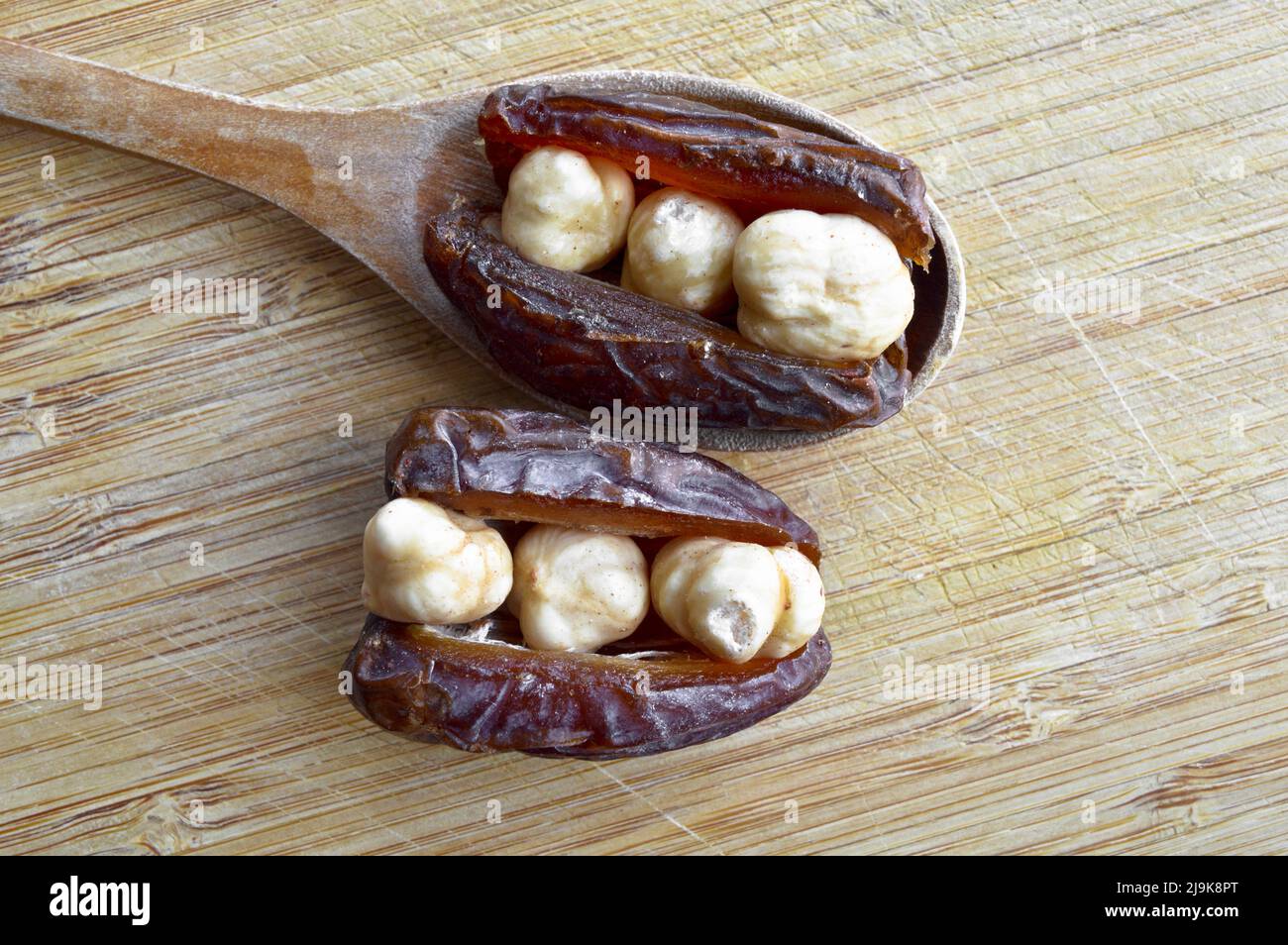 Hurma secco nutriente biologico fresco datteri chicchi di medjool, nocciole poste all'interno della data, sul tagliere, in cucchiaio di legno Foto Stock