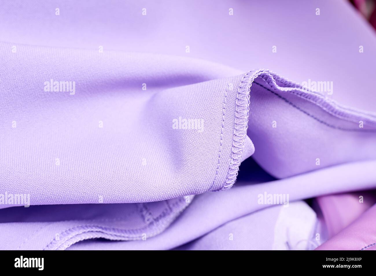 Primo piano di cuciture overlock e cuciture diritte su abito viola Foto Stock