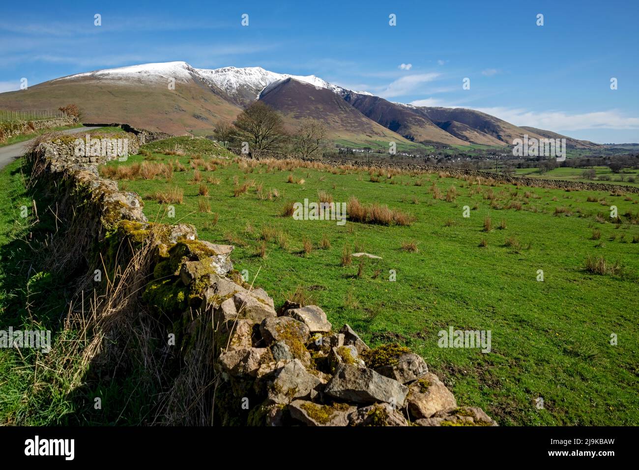 Vista verso il villaggio di Threlkeld e i terreni agricoli ricoperti di neve Blencathra in primavera a fine inverno Lake District National Park Cumbria Inghilterra UK Foto Stock