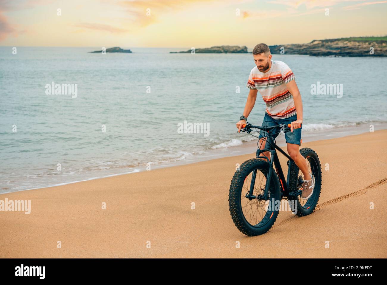 Uomo che guida una bici grassa sulla spiaggia Foto Stock