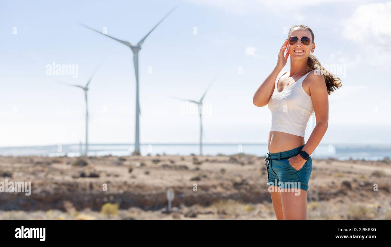 Giovane donna in piedi vicino ai generatori di vento. Wind eco energia concetto immagine con copyspace Foto Stock