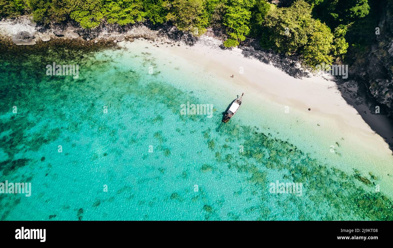 Barca a coda lunga tailandese ancorata su una spiaggia di sabbia bianca a Ko Kai (Chicken Rock Island) in Krabi Thailandia con acqua tropicale blu turchese e barriera corallina Foto Stock
