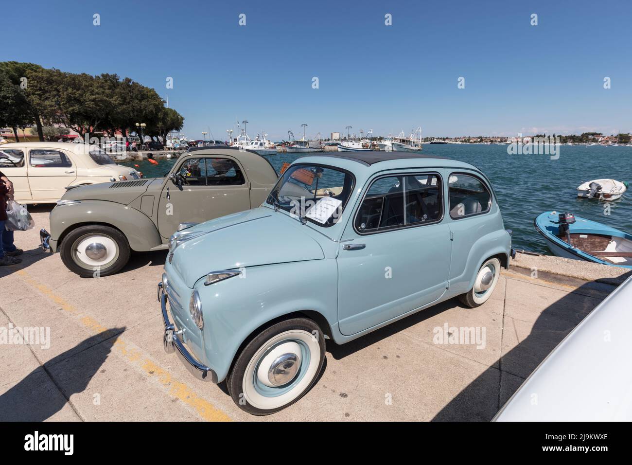 Fiat 600 e altre auto d'epoca si riuniscono per incontrarsi a Riva Umago, sul lungomare vicino al porto. Umago, Croazia Foto Stock