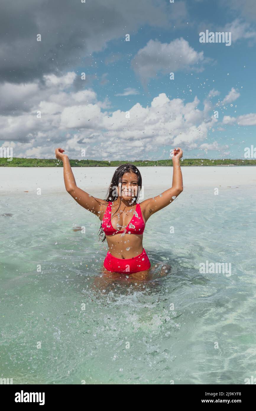 Giovane ragazza asiatica in acque turchesi dell'oceano con bikini rossi sull'isola privata di Leebong in Indonesia con una bellissima spiaggia di sabbia bianca Foto Stock