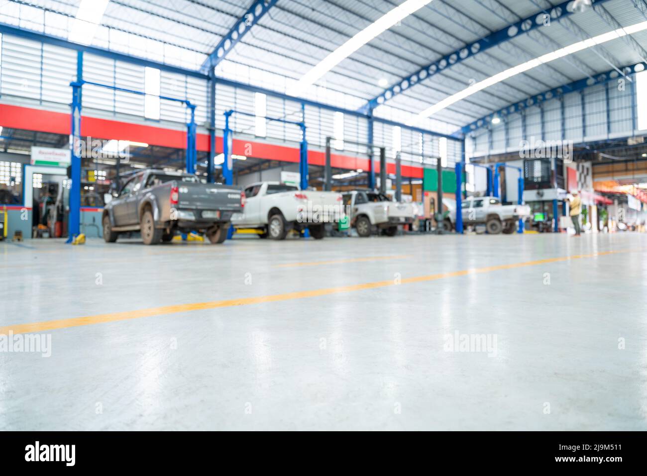 Sfondo sfocato della stazione di riparazione auto lastricata con pavimento epossidico e ascensore elettrico per una macchina che viene a cambiare l'olio motore sullo sfondo di C. Foto Stock