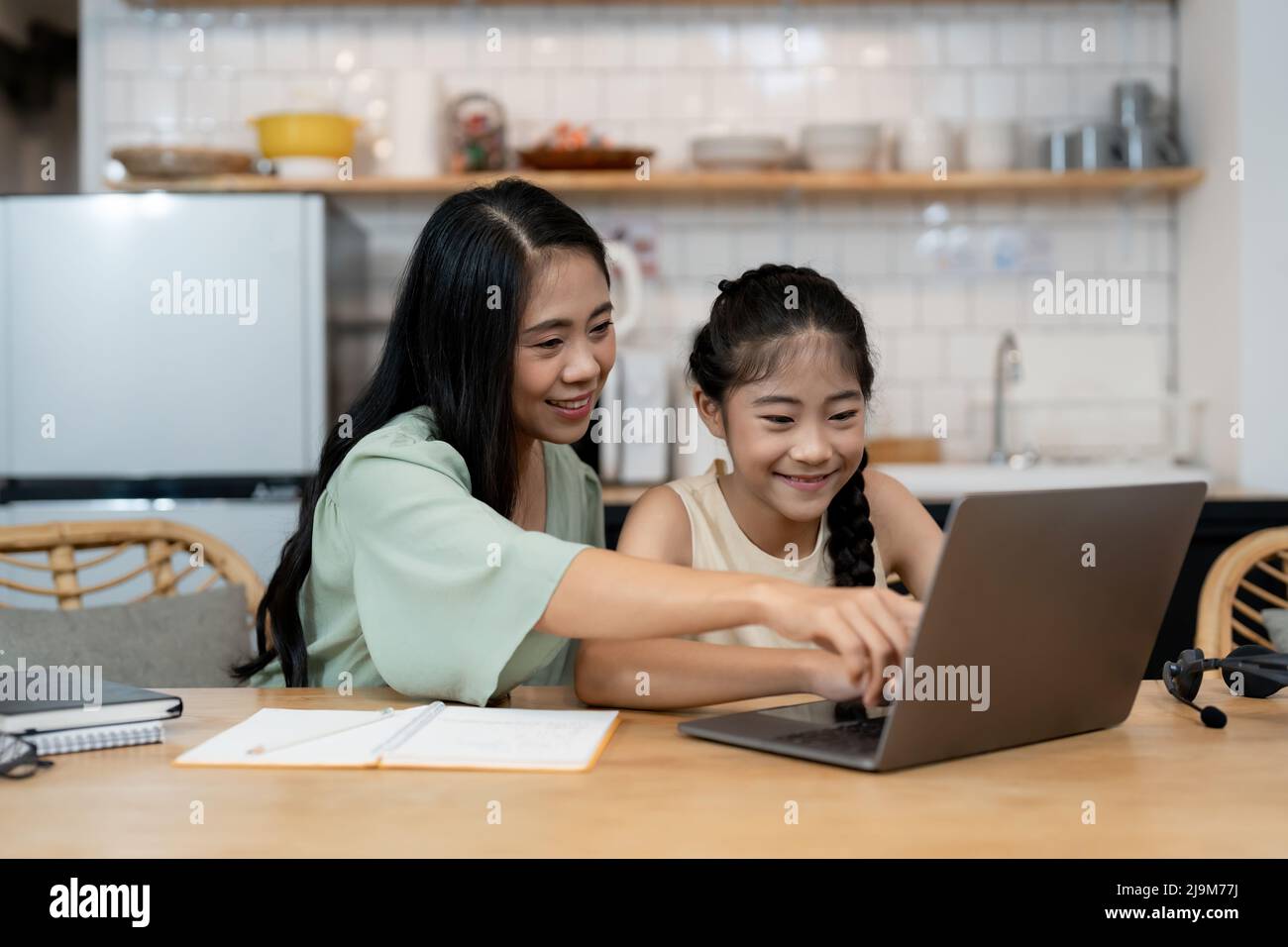 Madre che insegna ai bambini di fare i loro compiti a casa. Buona famiglia asiatica che usa il portatile insieme a casa. Giovani genitori asiatici famiglia aiutare Foto Stock