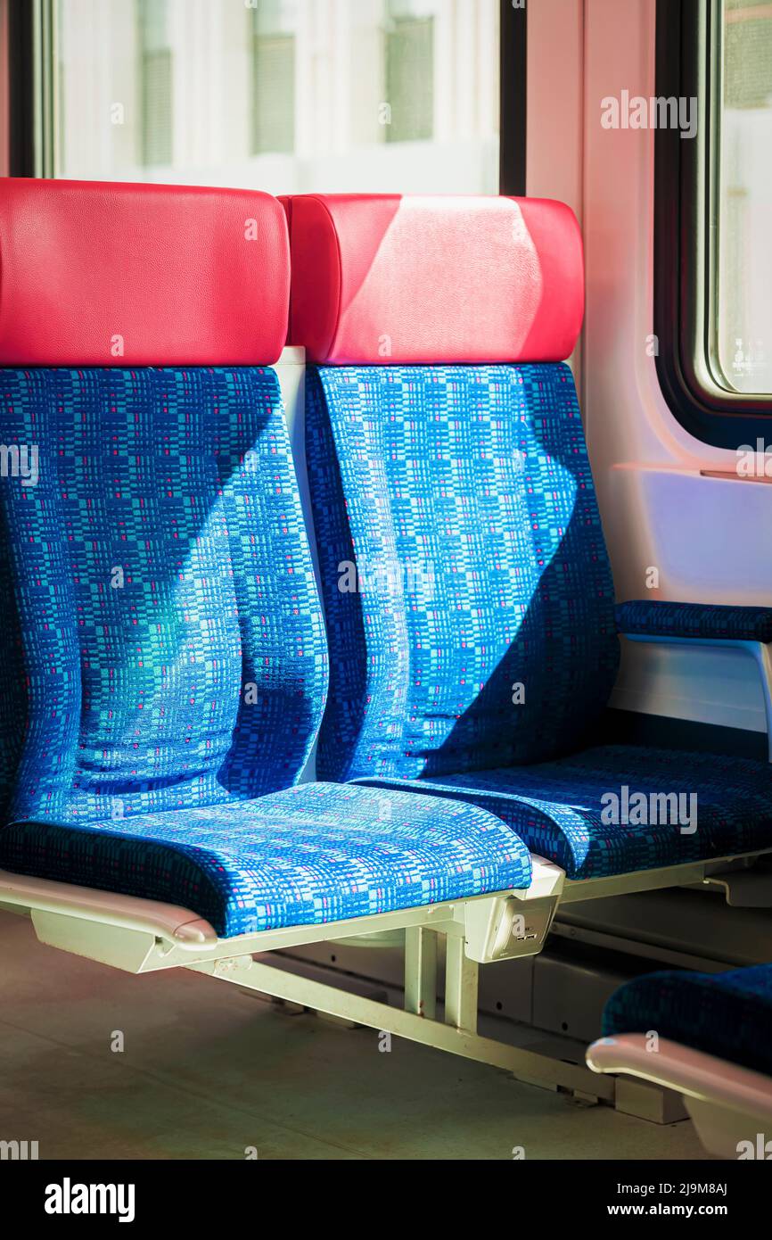 Sedili vuoti in tessuto blu rosso in primo piano, interni all'interno dei treni passeggeri o dei tram ferroviari. Concetto di trasporto pubblico Foto Stock