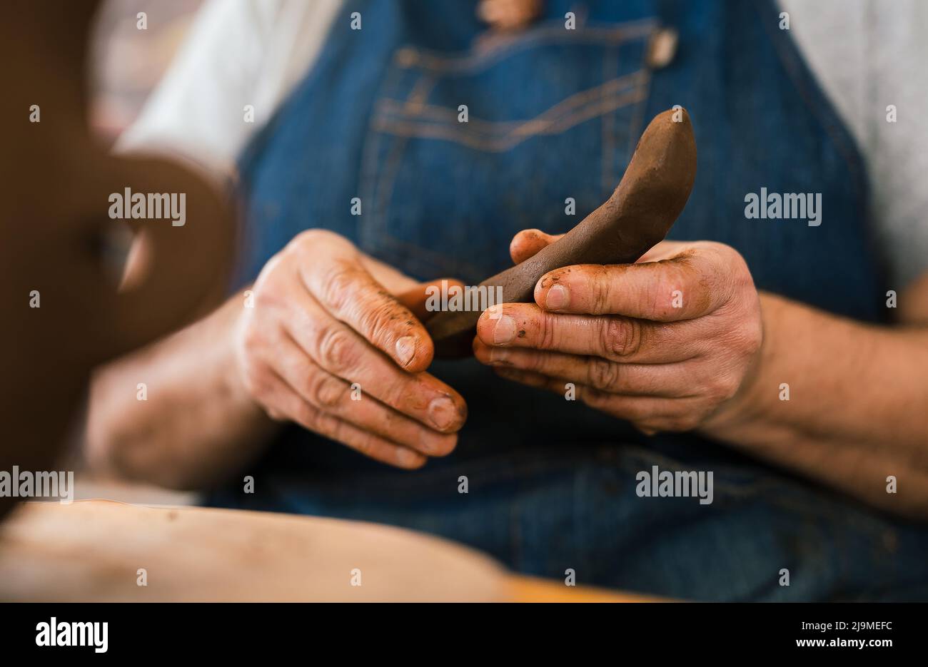 CraftsCraftsWoman ceramista in grembiule modellare pezzo di argilla in mano in officina Foto Stock