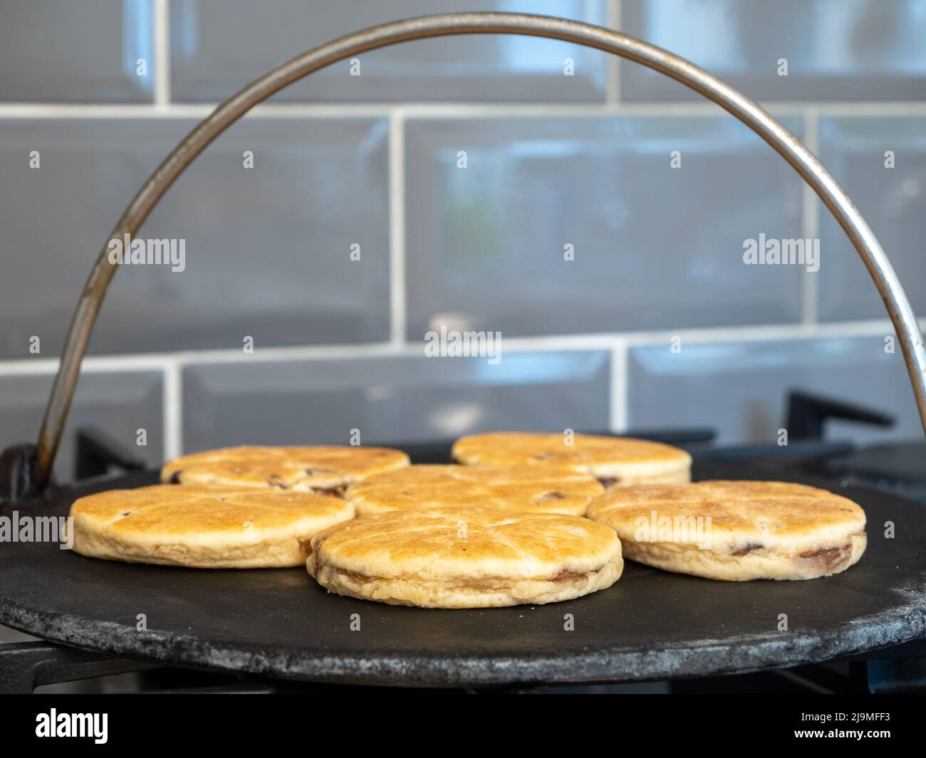 Focus selezionato torte gallesi cottura su una griglia in ghisa su una fiamma del piano cottura a gas Foto Stock