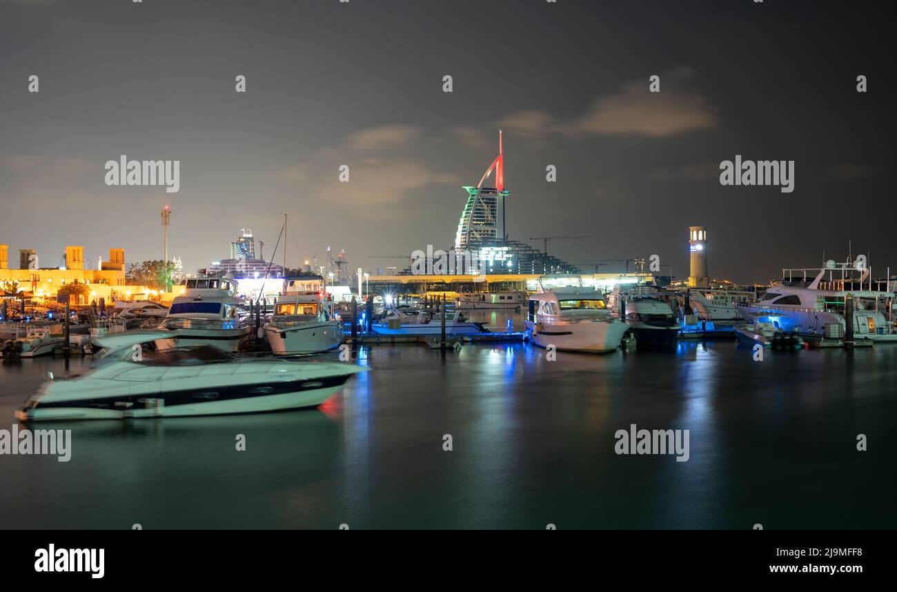 Vista notturna illuminata dell'hotel Burj al Arab, un iconico hotel a sette stelle a Dubai, insieme alle navi nel molo catturate dal Burj al Arab Foto Stock