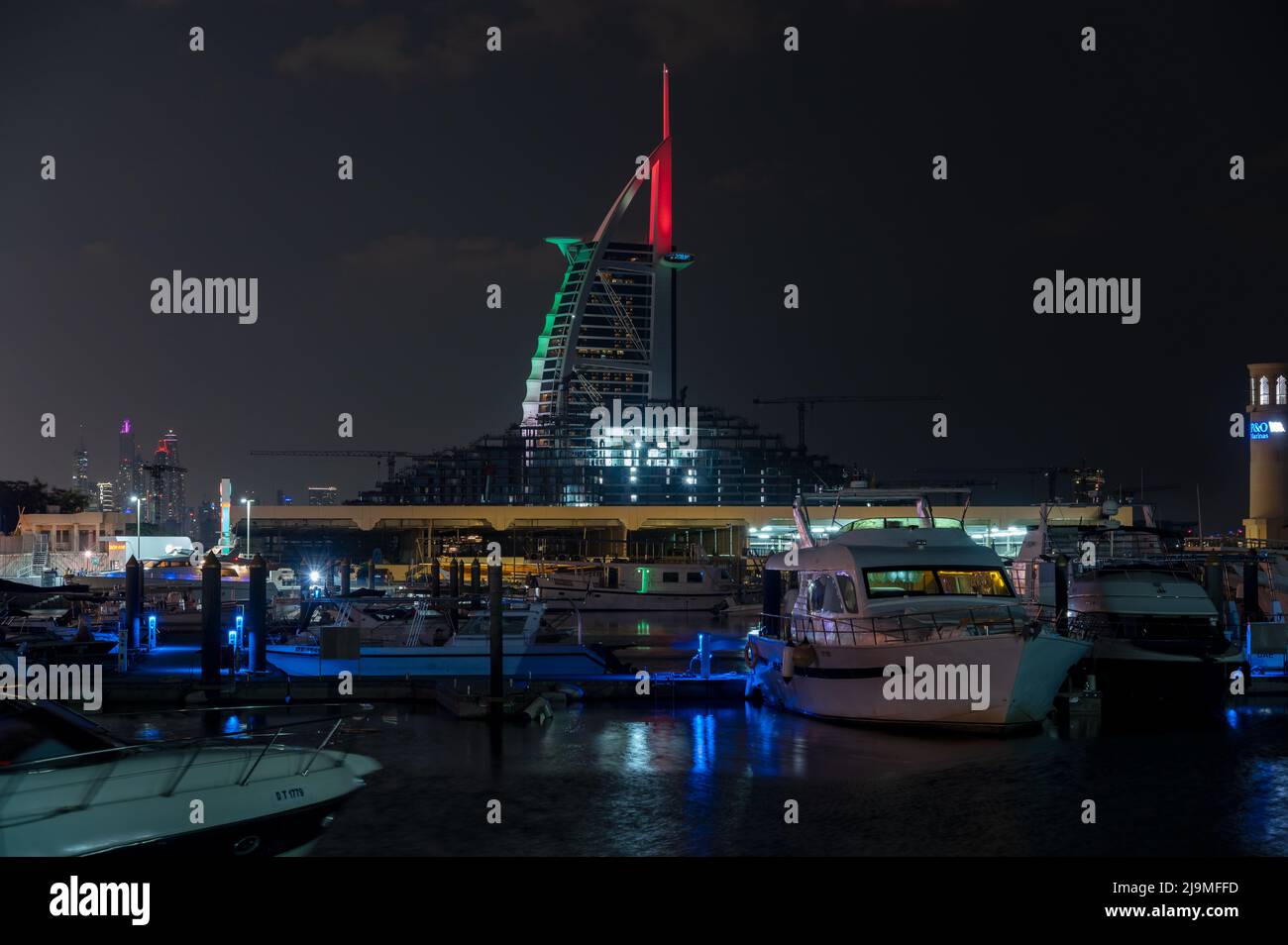 Vista notturna illuminata dell'hotel Burj al Arab, un iconico hotel a sette stelle a Dubai, insieme alle navi nel molo catturate dal Burj al Arab Foto Stock