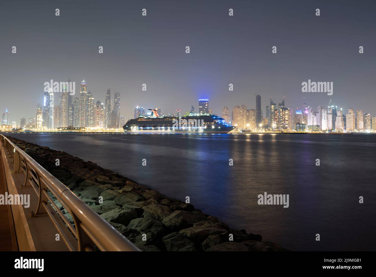 Splendida nave da crociera illuminata al molo di Palm Marina insieme agli edifici di Dubai Marina catturati da Palm Jumeirah Foto Stock