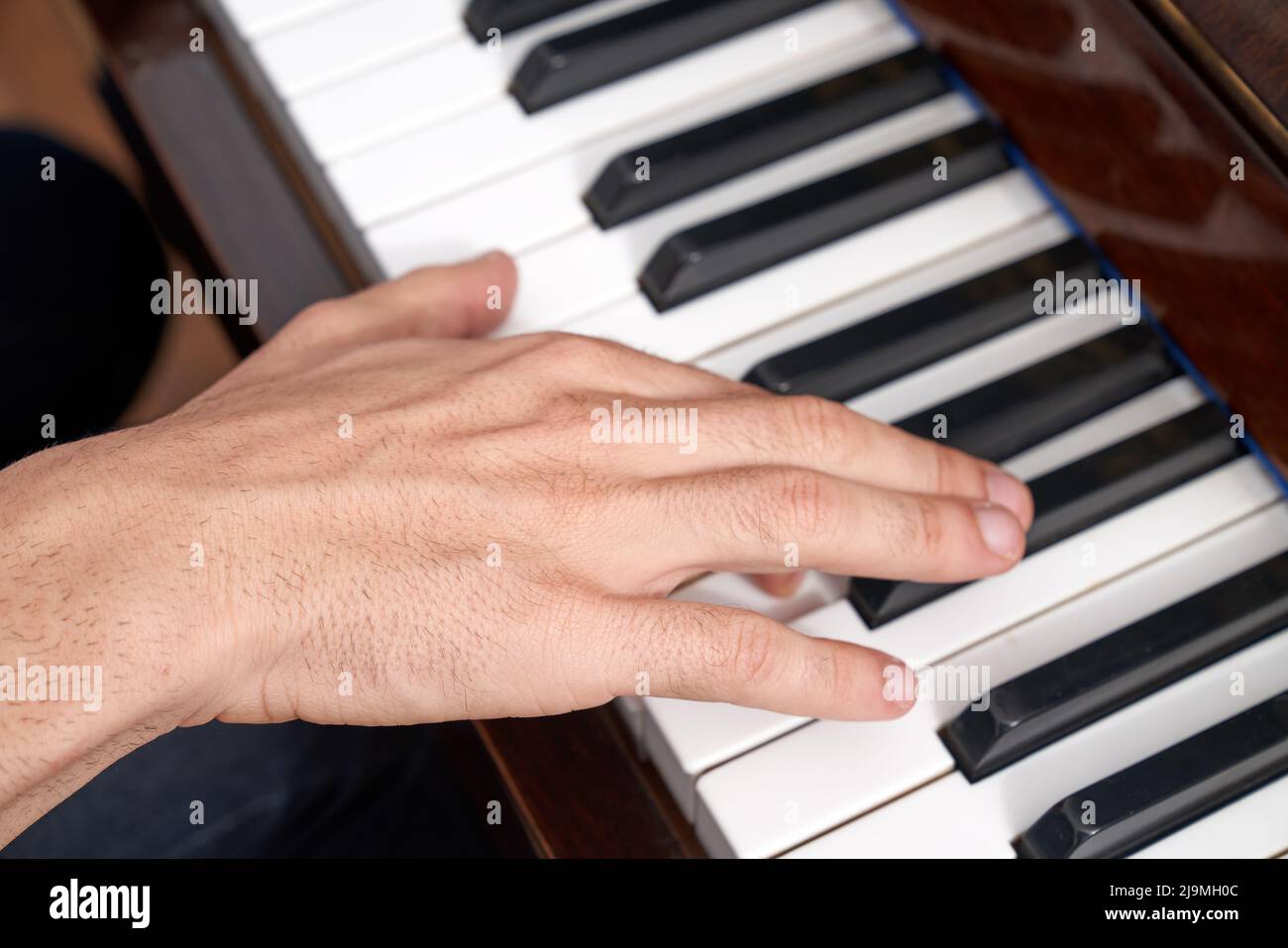 Crop anonimo confettioner femminile in grembiule e guanti preparazione deliziosa dolce decorato con cioccolato commestibile colorato in camera luminosa Foto Stock