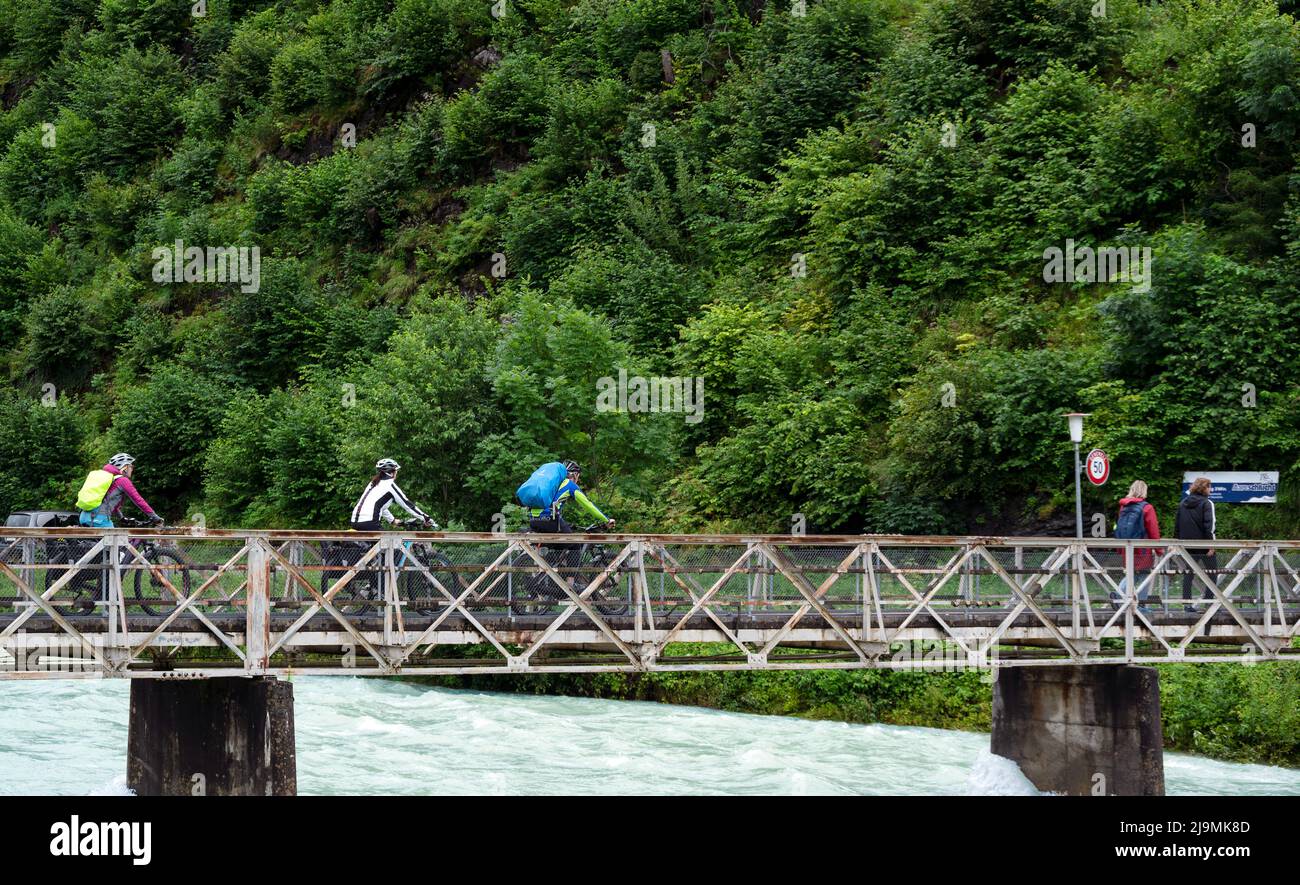 Ciclisti che indossano caschi e zaino, pedalano su un ponte sul fiume Aare catturato ad Aareschlucht in Svizzera. Foto Stock
