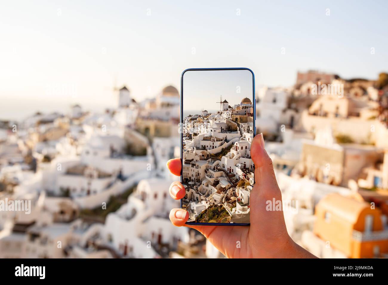 Fotografare un punto di riferimento utilizzando una fotocamera del telefono cellulare. Vista famosa di Santorini in Grecia sullo schermo di uno smartphone Foto Stock