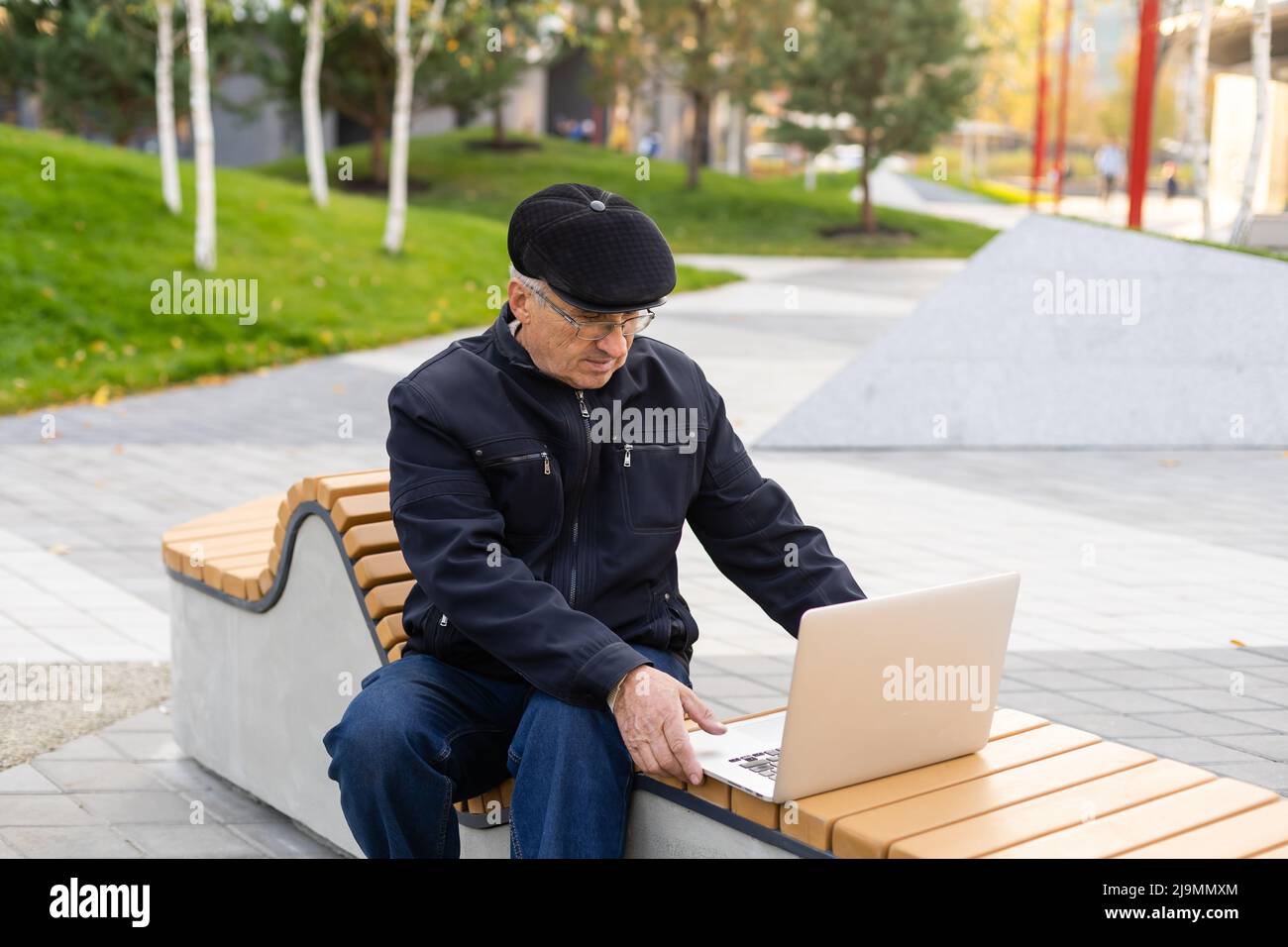 uomo anziano con computer portatile nel parco autunnale. Foto Stock