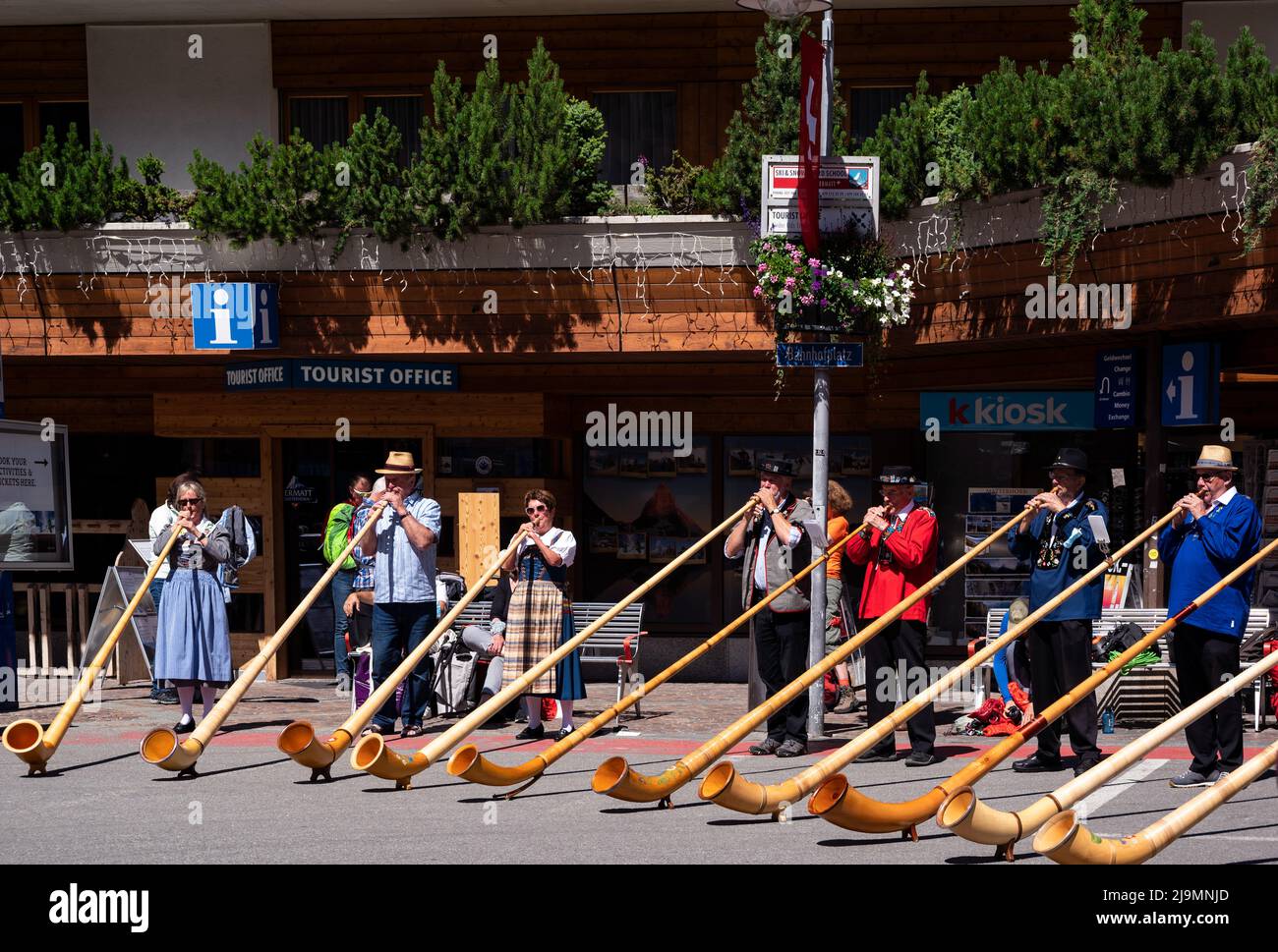 I musicisti svizzeri suonano l'alphorn, uno strumento musicale tradizionale guidato da un direttore del coro sulla strada principale del villaggio di Zermatt. Foto Stock