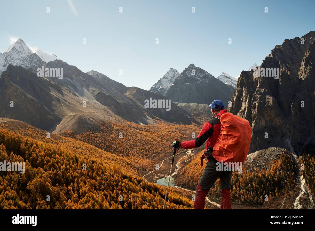 vista posteriore di un escursionista asiatico che guarda la valle del fiume nelle montagne nel parco nazionale yading, contea di daocheng, provincia di sichuan, cina Foto Stock