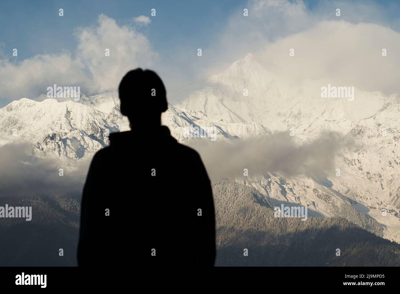 vista posteriore di un ragazzo asiatico che guarda la montagna di neve meili a yunnan, cina Foto Stock