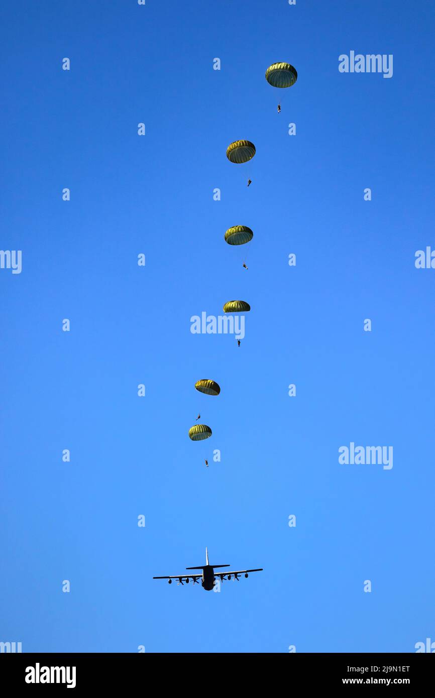 Paracadutisti militari paracadutisti paracadutisti che saltano fuori da un aereo di forze aeree in una giornata di cielo blu chiaro. Foto Stock