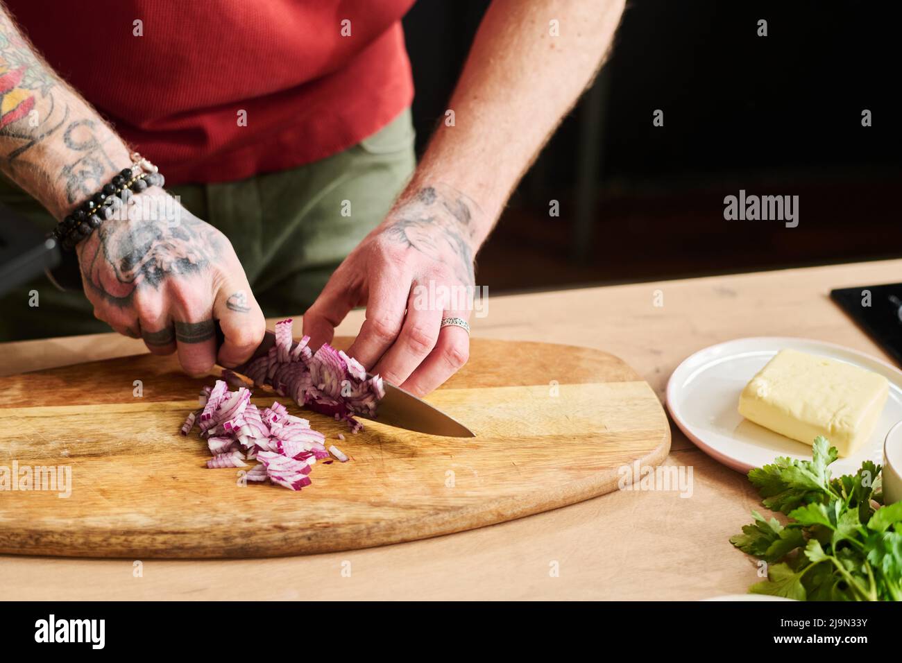 Primo piano di un uomo irriconoscibile che trita cipolla rossa su tagliere  di legno con coltello Foto stock - Alamy